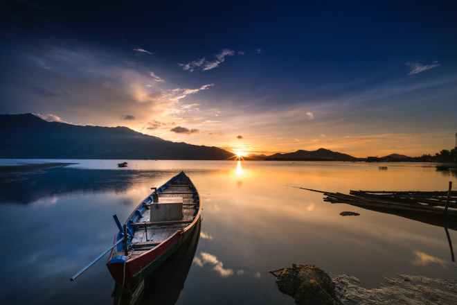 empty gray canoe boat near shore during golden hour